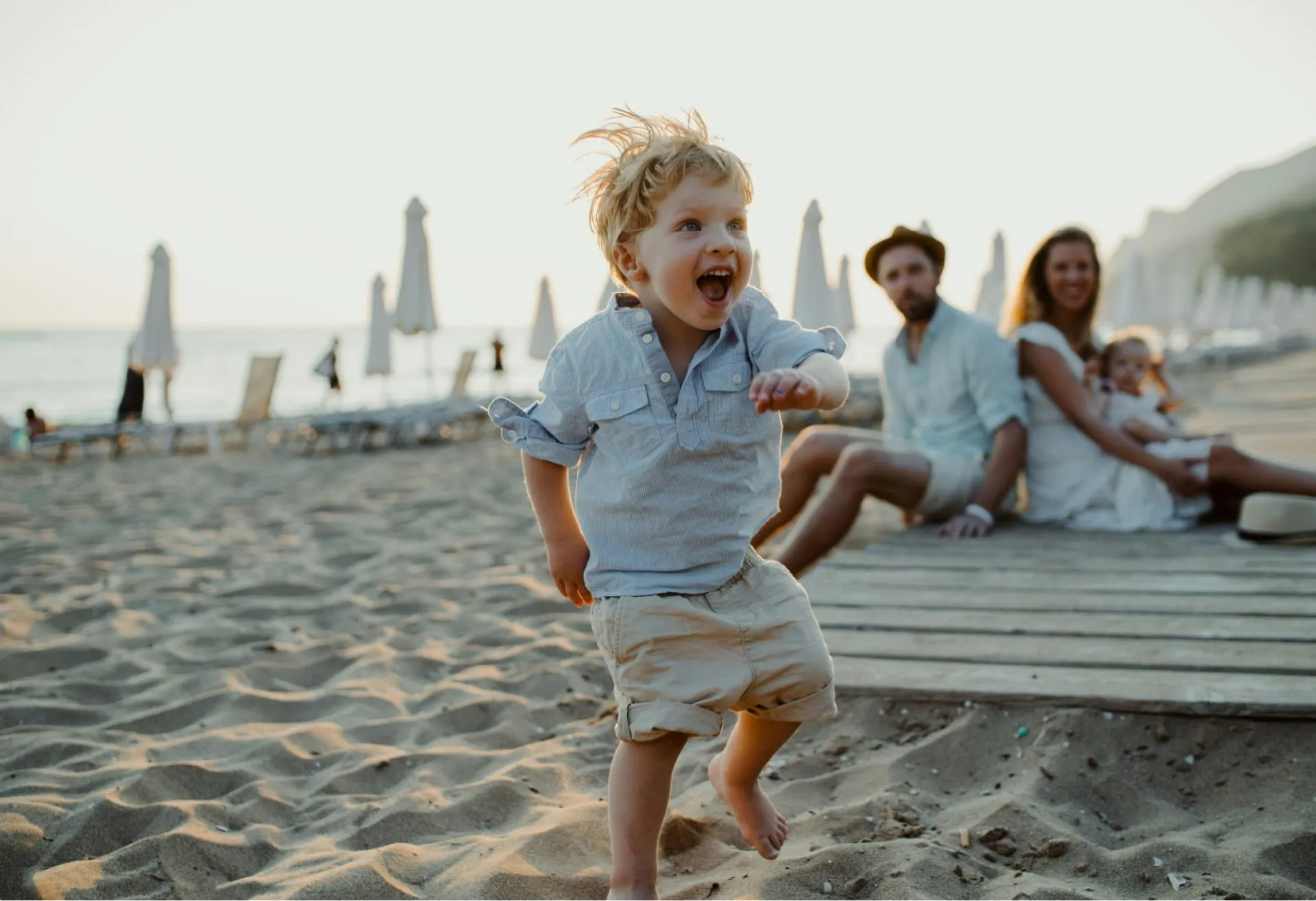 Primer plano de un niño pequeño disfrutando de la playa con su familia de fondo